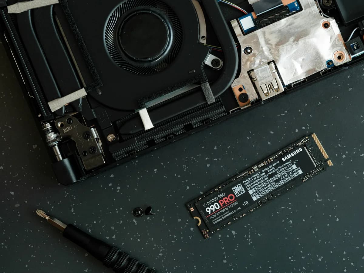 Notebook aberto na bancada, com SSD M.2 e chave de precisão ao lado
